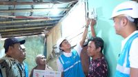 Warga kelurahan Cakung Timur, Jakarta Timur Syukur (dua dari kanan) yang menjadi penerima manfaat program Light Up The Dream menyalakan listrik di rumahnya bersama Senior Manager Niaga dan Pelayanan Pelanggan PLN Unit Induk Distribusi Jakarta Raya, Inu Suprianto (tiga dari kanan).