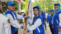Bupati Halbar James Uang menyerahkan bendera pataka kepada Ketua Kontingen, Hj. Chuzaemah Djauhar di halaman Kantor Bupati. (Istimewa)